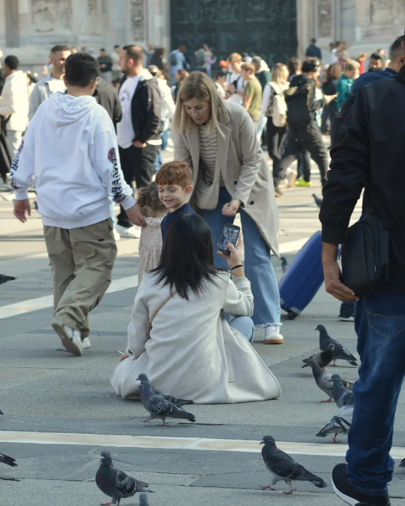 A mother and her young son among the pigeons in a busy Milan piazza
