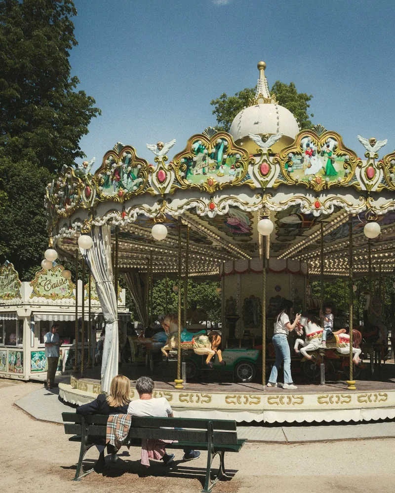 Parents and children by the carousel in the Tuileries Garden, Paris, on a sunny day